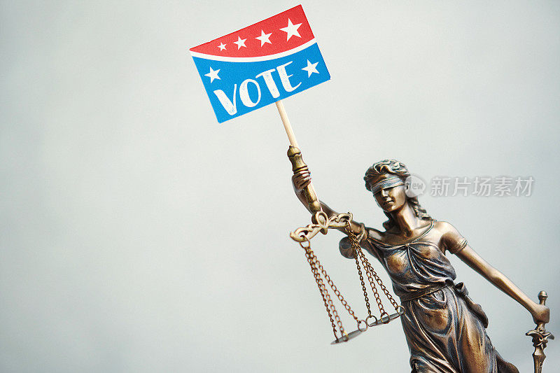 Lady Justice with reminder to vote sign
